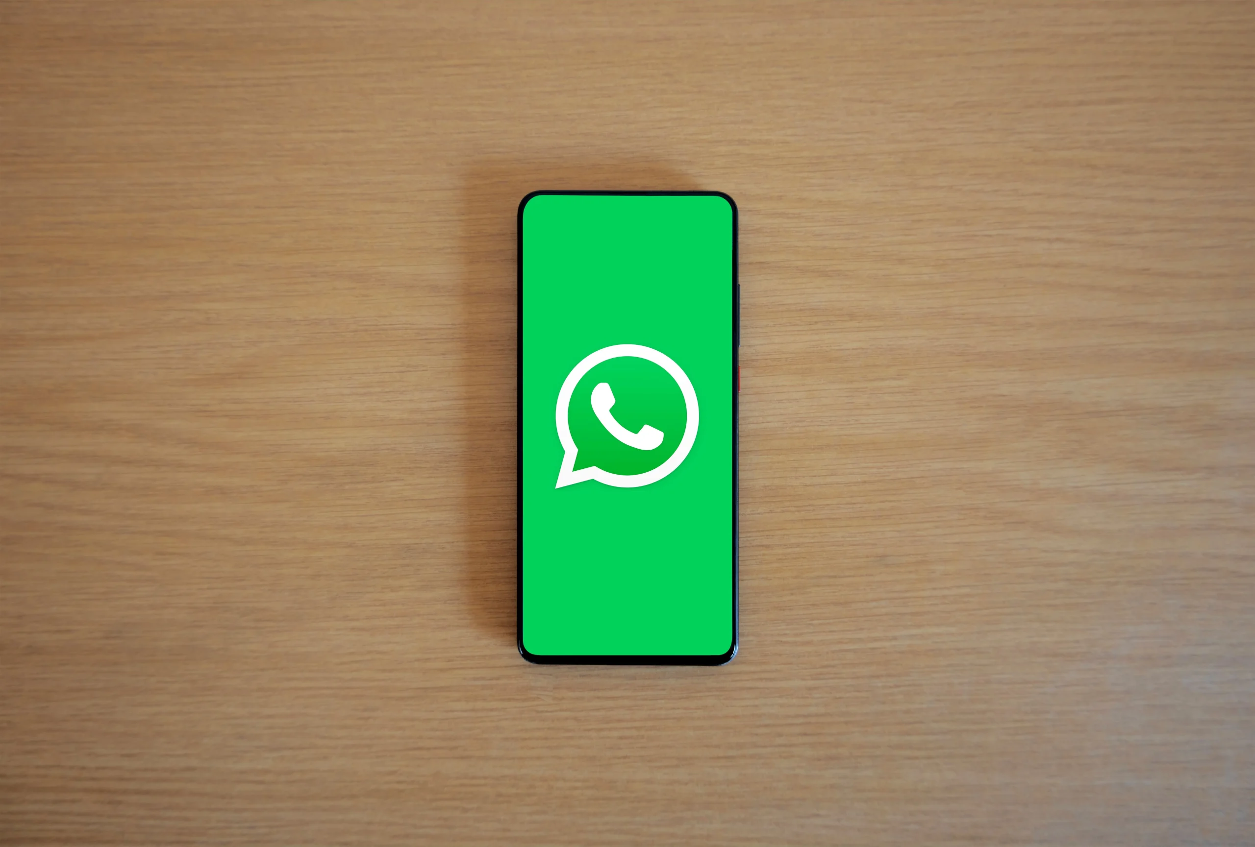 A Smartphone Displaying Whatsapp Logo On A Wooden Background Scaled 1